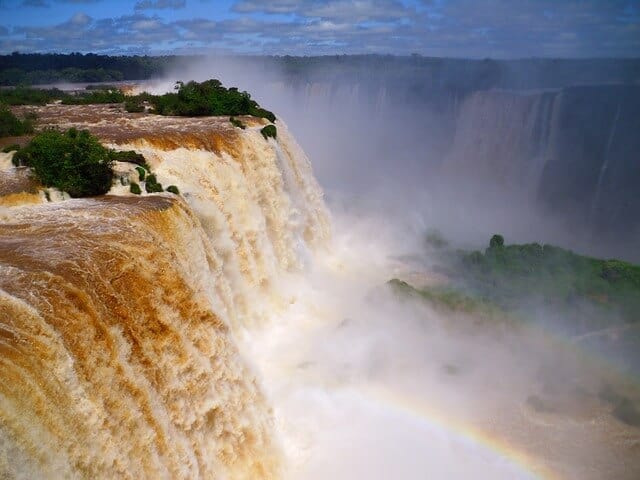 Iguaçu Falls cascading past forested cliffs into clouds of spray
