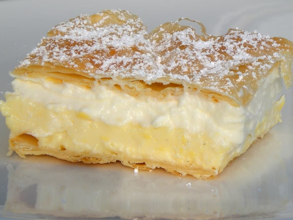 A slice of Bled cream cake with pastry, custard, cream and powdered sugar