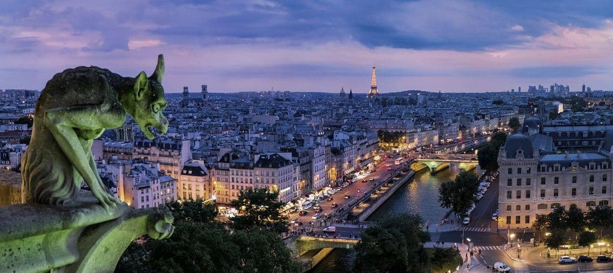 Stone gargoyle overlooking the Seine and Paris skyline at dusk