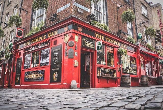 The red exterior of The Temple Bar pub beside a cobbled street in Dublin
