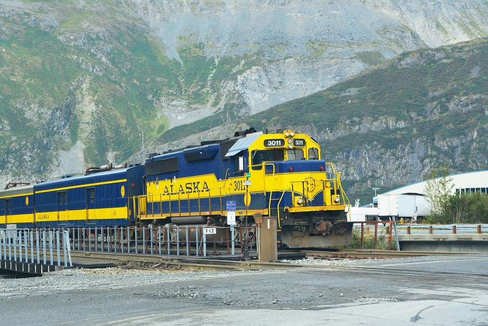 Blue and yellow Alaska Railroad locomotive beneath mountains