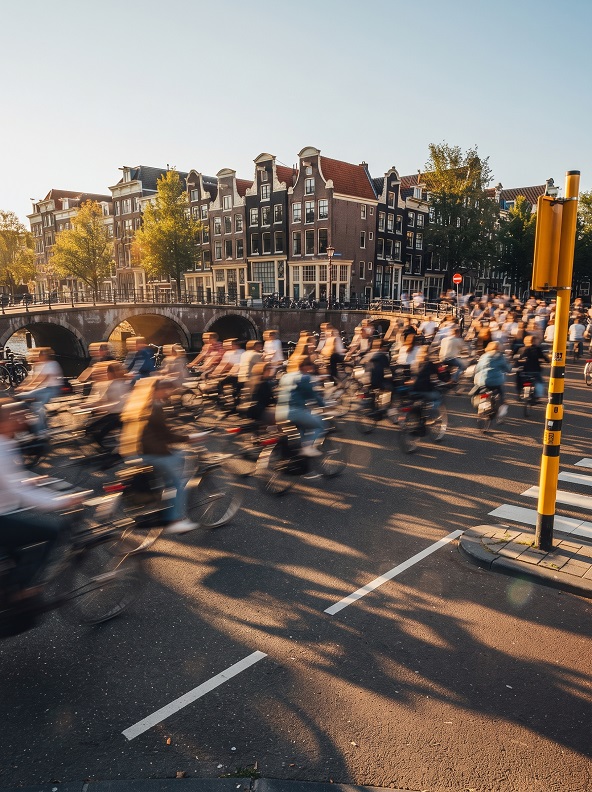 Cyclists crossing an Amsterdam intersection beside canal houses