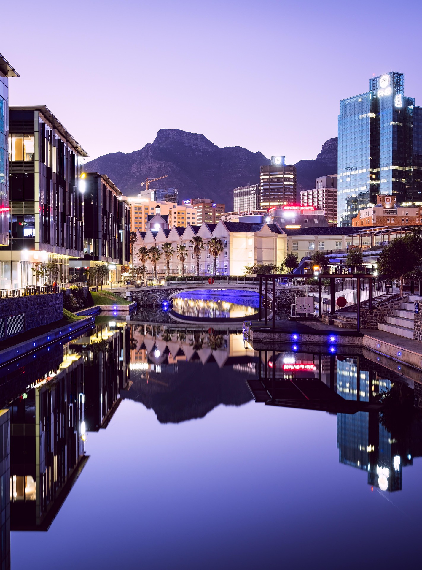 Cape Town canal-side buildings reflected in the water at dusk with Table Mountain behind