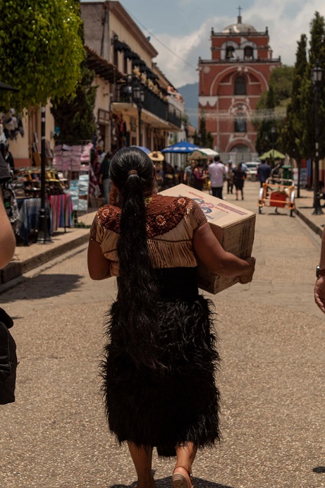 Woman carrying a box along a busy street in Chiapas