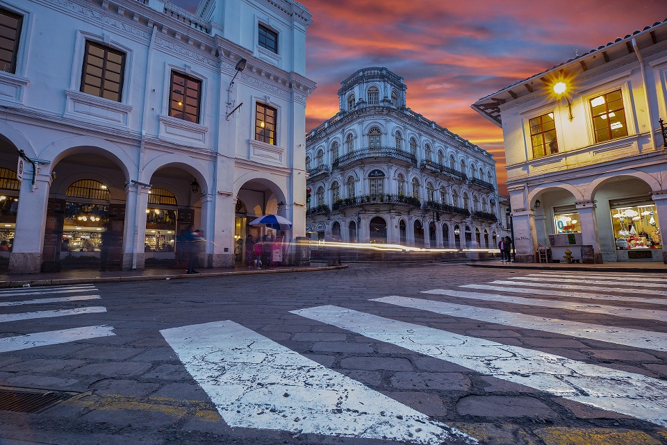 Historic buildings and a street crossing at sunset in Ecuador