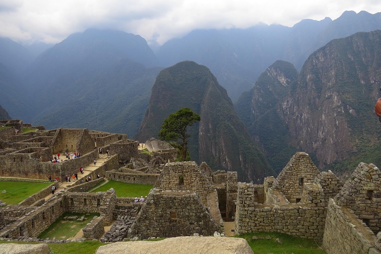 Stone buildings at Machu Picchu beneath misty Andean mountains in Peru