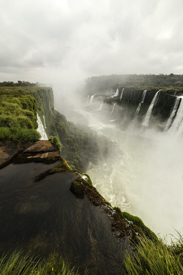 Iguazú Falls plunging between forested cliffs into clouds of spray