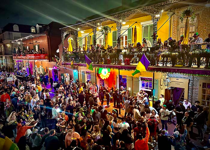 Crowds celebrating beneath decorated New Orleans balconies