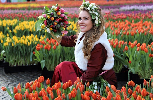 Woman holding a bouquet among colourful tulip displays