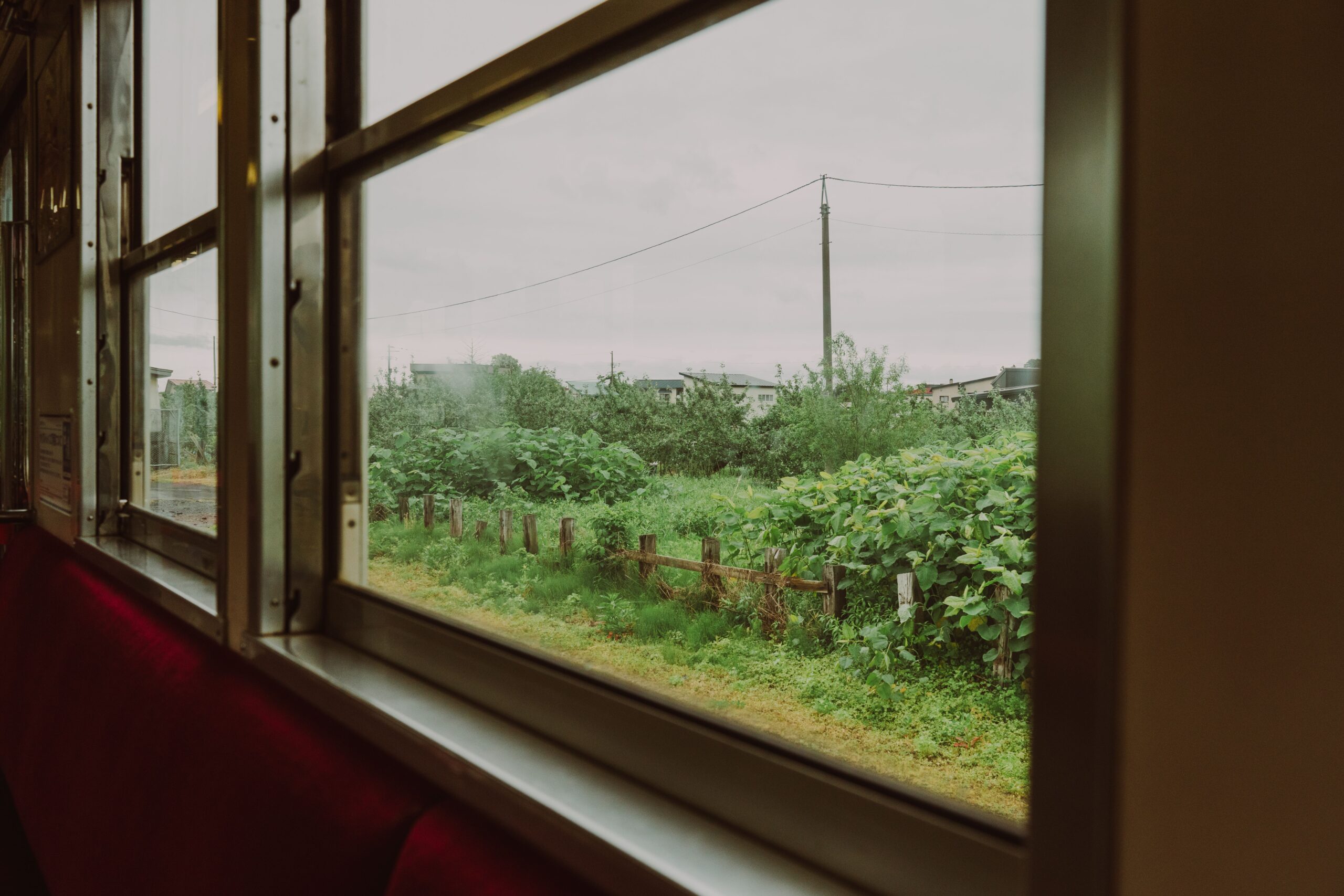 View through a train window toward nearby countryside, suggesting an easy day trip by rail