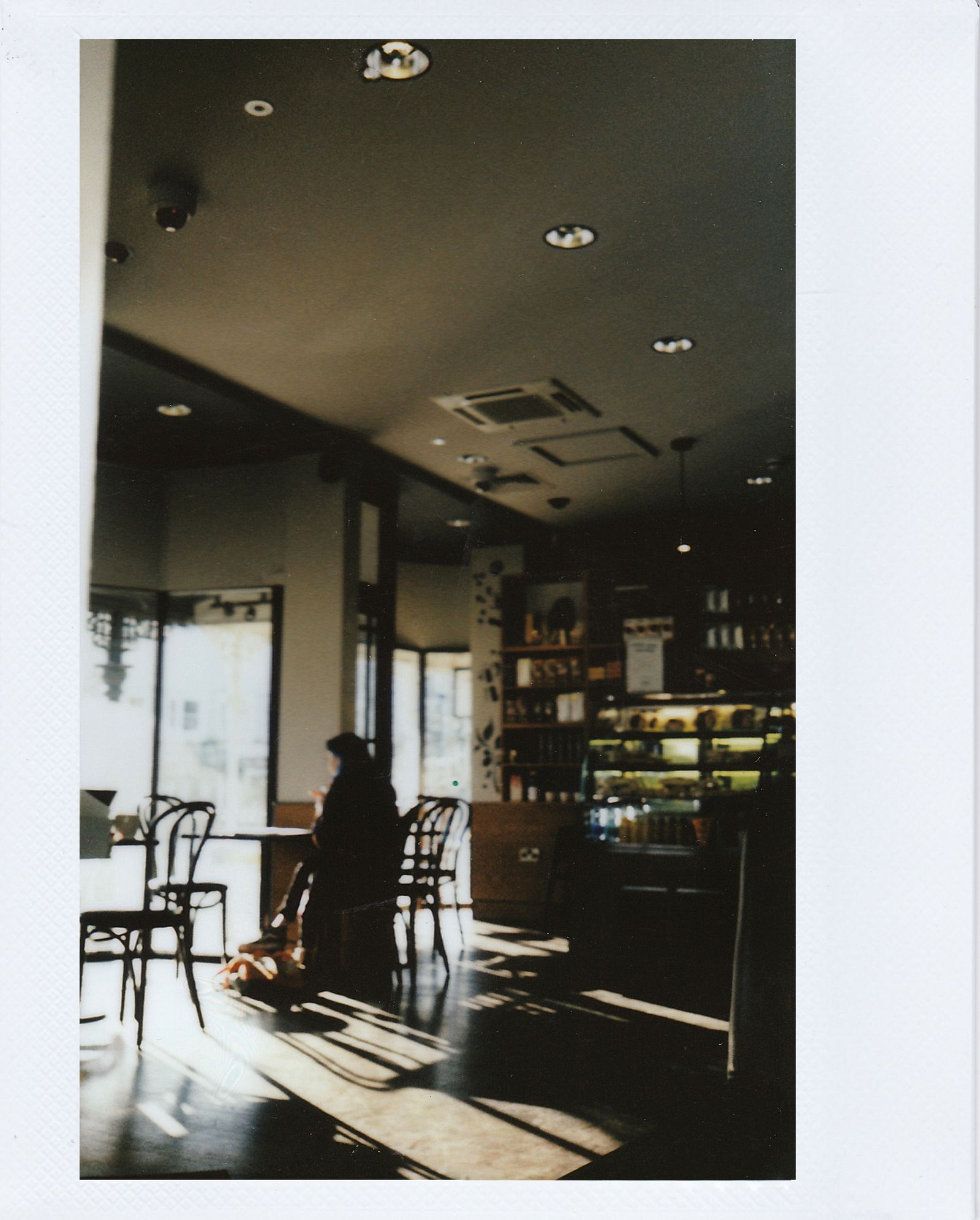 Person seated alone at a table in a warmly lit café