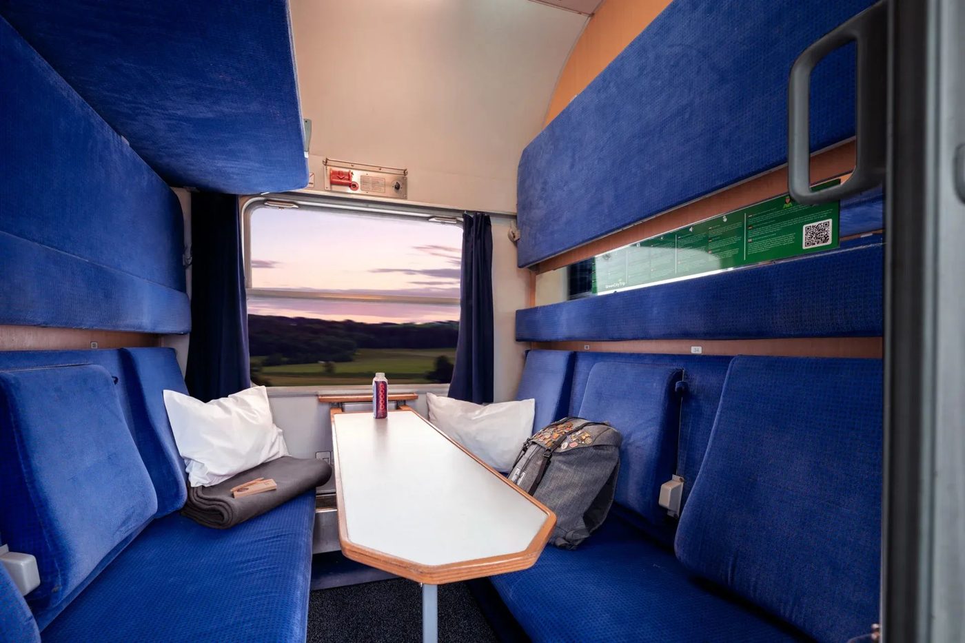 Blue seats and upper bunks in a shared night train couchette compartment