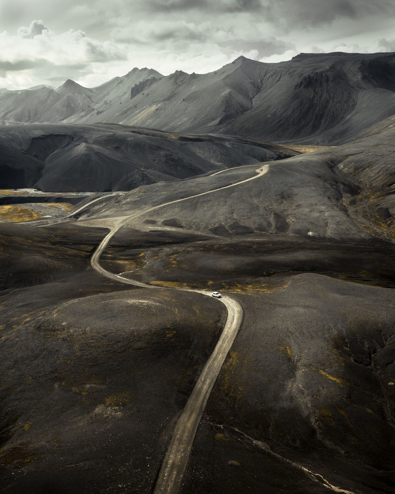 A winding road through rugged mountains beneath a cloudy sky