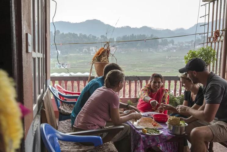 Five people preparing food together on a veranda
