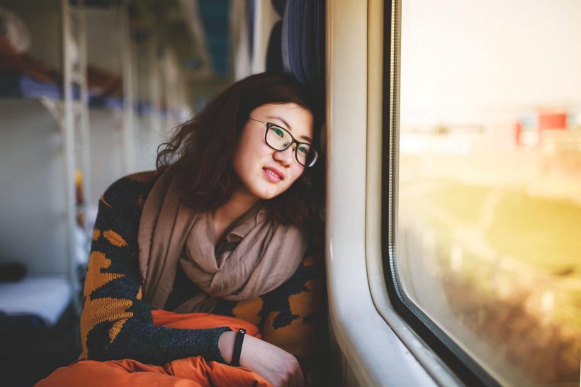 Woman wearing glasses looking out of a train window